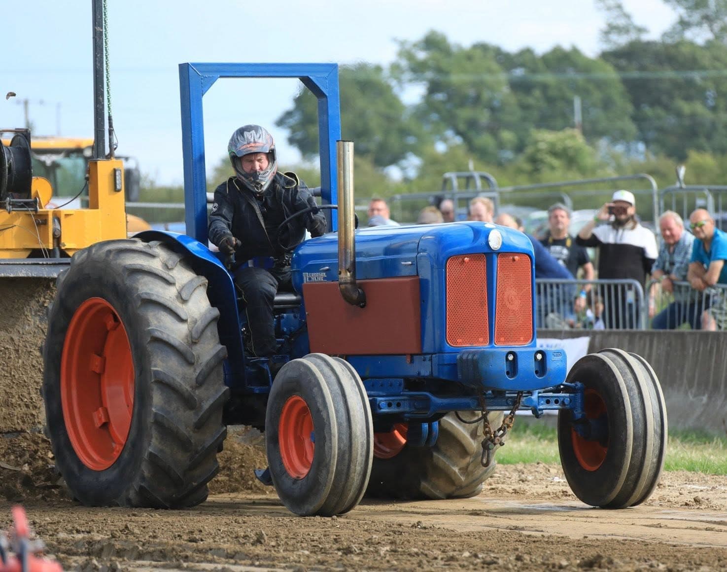 A tractor pulling the weighted sled along the track, with spectators watching